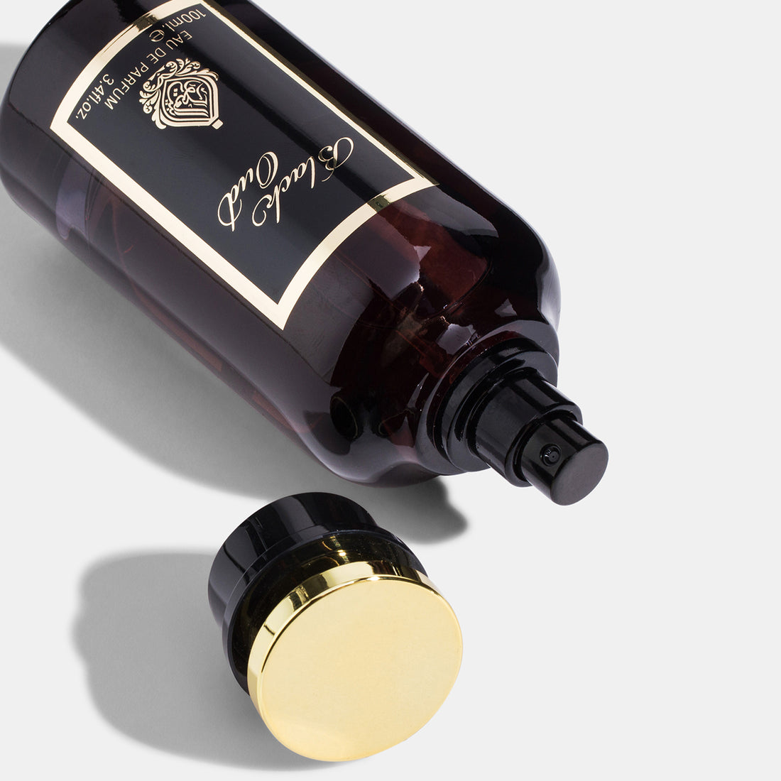 A dark amber glass perfume bottle with a gold-colored cap, labeled 'Black Oud Eau de Parfum 100ml'.