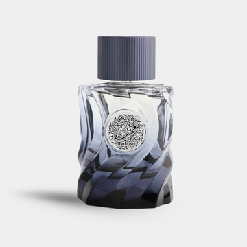 A faceted glass perfume bottle with a dark blue gradient and a ribbed dark cap, featuring a silver circular emblem on the front.