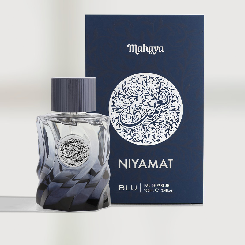 A faceted glass perfume bottle with a dark blue gradient and a ribbed dark cap, featuring a silver circular emblem on the front.