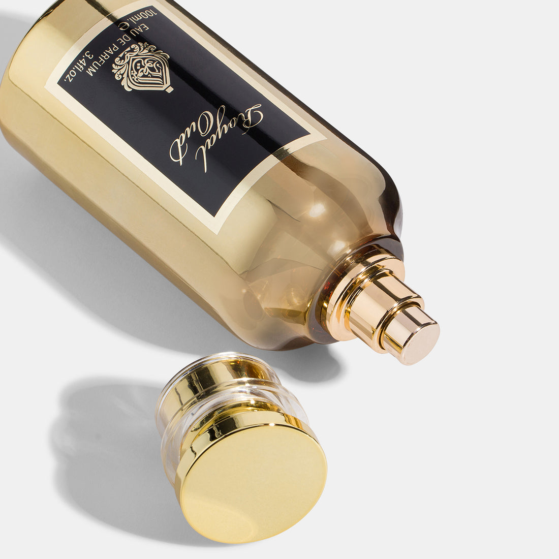 A gold-colored bottle of 'Royal Oud' cologne with a black label and a golden cap.